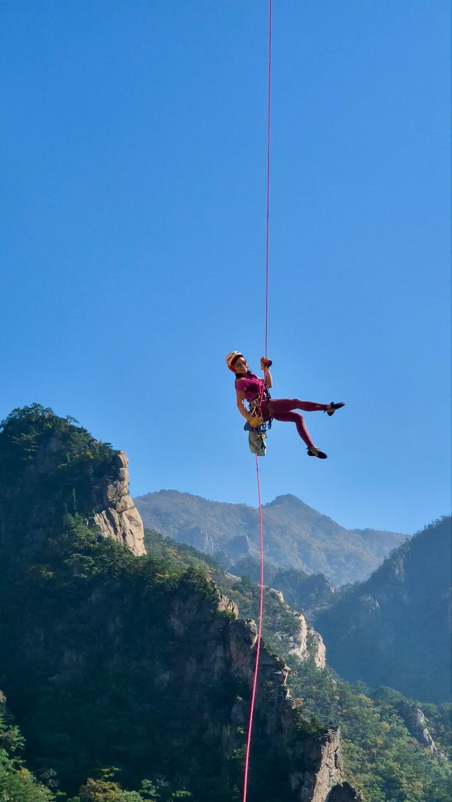 Maria Ly rappeling mid-air over mountain cliffs